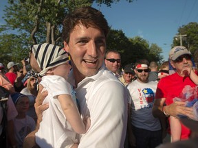 Federal Liberal leader Justin Trudeau holds a baby as he campaigns in the riding of Acadie-Bathurst  as he attends an Acadian festival in Caraquet, N.B. on Saturday, August 15, 2015. (CANADIAN PRESS/Andrew Vaughan)