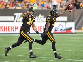 Tiger-Cats defensive backs Donald Washington (right) and Mike Daly celebrate after Washington recovered a B.C. Lions fumble during the first half in Hamilton on Saturday night. Defence played a huge part in the Ticats’ 52-22 victory. (The Canadian Press)