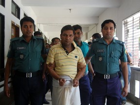 Bangladeshi police escort a man linked to the beating death of a 13-year-old boy in Sylhet on July 13, 2015. Bangladesh police were hunting a group of attackers July 13 who lashed a 13-year-old boy to a stake and then beat him to death, filming the onslaught on a smart phone.  The 28-minute video, in which the boy is seen begging for water as he lay dying in the northeastern city of Sylhet, has sparked huge protests in Bangladesh since it went viral on social media over the weekend.  (AFP PHOTO)