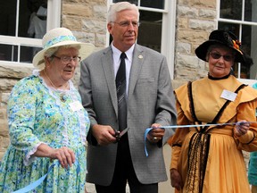 From left, Barb Stewart, chair of the Portland and District Heritage Society, and Ron Vandewal, mayor of South Frontenac, and Lynne Hutcheson, member of the Heritage Society,  cut the ribbon to officially open the South Frontenac Museum in Hartington on Saturday. (Steph Crosier/The Whig-Standard)