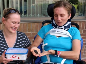 Parkwood Institute patient Julie Sawchuk, right, holds a snapping turtle named after her while talking with Huron Stewardship Council species at risk technician and friend Jory Mullen outside of the facility in London, Ont. on Monday August 17, 2015.  Sawchuk survived a recent bicycle crash that left her with a broken back and neck. (EMANUELA CAMPANELLA, The London Free Press)