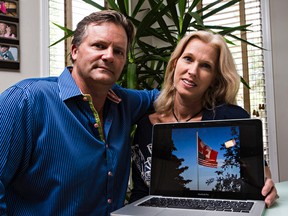 Steve and Caroline Thompson pose with a photo of the Canadian and USA flags they had flying in their backyard at their home in Edmonton.. The couple say someone ripped their American flag down last week. (CODIE MCLACHLAN/Edmonton SUn).