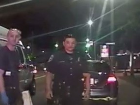 Police officers are embraced by a man who's baby they just delivered on the side of the road in Seattle. (YouTube/Screengrab)