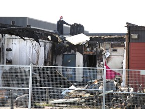 A fire inspector walks on the roof of school portables at Ecole Frere Antoine School in Edmonton, Alberta on Thursday, August 13, 2015. One of the portables was destroyed completely by fire. Perry Mah/Edmonton Sun