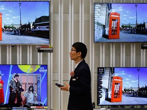 An employee uses his mobile phone in front of LG Electronics' organic light-emitting diode (OLED) TV sets, which are made with LG Display flat screens, at its store in Seoul Jan. 28, 2015. REUTERS/Kim Hong-Ji