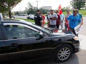 Airport Taxi driver Salim Mankal (right) and others block a Blueline cab at the headquarters of Coventry Connections, the company that in conjunction with the Ottawa Airport Authority wants to charge drivers $5.00 per fare at the airport. Tuesday August 18, 2015. Errol McGihon/Ottawa Sun/Postmedia Network