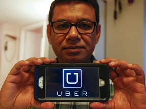 Tawfiqul Alamon poses with a smartphone displaying the Uber taxi service logo Tuesday August 18, 2015. (Jack Boland/Toronto Sun)