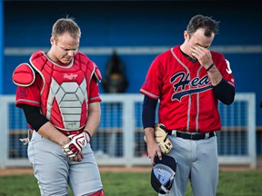 John O'Dell, left, and Justin Turner, right, with the Edmonton firefighters' baseball team the Heat take a moment of silence honour their fallen comrade, Ryan Soneff, at Wally Footz Field in Edmonton, Alta. on Tuesday, Aug. 18, 2015. Soneff passed away Tuesday after battling terminal brain cancer.
