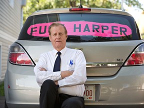 Rob Wells stands with his Steven Harper sign he put in his vehicle's rear window in Edmonton Alta, on Wednesday Aug 19, 2015. Wells has been fined $543 by police for having the sign in his car. (THE CANADIAN PRESS/Jason Franson)