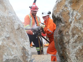 Mario Denis, left, of Boart Longyear, looks on as Natahsa James, of Gorf Manufacturing, takes part in the media and celebrity jackleg challenge at the North American Mine Expo in Copper Cliff, Ont. on Wednesday, August 19, 2015. John Lappa/Sudbury Star