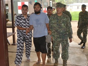Escaped hostage Philippine coast guard Seaman First Class (SN1) Rod Pagaling, center, is escorted inside a military camp in Jolo, Sulu province, southern Philippines Thursday, Aug. 20, 2015. (AP Photo/Nickee Butlangan)