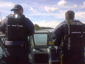 A photograph of two RCMP officers patrolling the North Saskatchewan River by boat on August 20, 2015