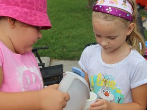 SAMANTHA REED/FOR THE INTELLIGENCER
Six-year-old Lauren holds a cup as Sophia, 6, pours lemonade into a cup for a customer, while selling lemonade on Lewis Street in Belleville Thursday morning.  This is the second year Bev Johnson and her daycare have held a lemonade stand to raise money for the Quinte Humane Society.