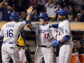 A.J. Ellis (middle) of the Los Angeles Dodgers is congratulated by Andre Ethier (left) and Carl Crawford after he hit a home run against the Oakland Athletics at O.co Coliseum on August 18, 2015 in Oakland. (Ezra Shaw/Getty Images/AFP)