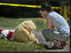 An unidentified young woman weeps next to a slumped-over teddy bear that was placed outside a Medicine Hat home in which three people, including an eight-year-old boy, were murdered on April 23, 2006. Postmedia files
