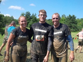 Tanya Dyke, left, and brothers Jonathan van Wyk and Brian van Wyk wear their mud-spattered #stthomasproud T-shirts at Tough Mudder competition last weekend north of Toronto.