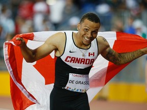 Canadian Andre De Grasse drapes himself with the flag after winning the gold medal in the Pan Am Games 100-metres at the CIBC Athletic Centre in Toronto on Wednesday July 22, 2015. (Stan Behal/Toronto Sun/Postmedia Network)
