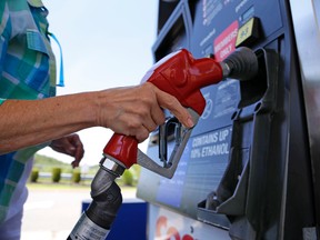 In this July 16, 2015 photo, a woman holds a nozzle as she refuels her car at a Costco gas station in Robinson Township, Pa. (AP Photo/Gene J. Puskar)