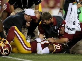 Redskins QB Robert Griffin III is examined after being sacked by Corey Wootton during a pre-season game against the Lions on Thursday. (Getty Images/AFP)