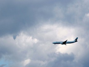 An Air Canada plane comes in for a landing past a small nubbin of funnel cloud near Calgary International Airport in Calgary, Ab., on Sunday July 26, 2015. Mike Drew/Postmedia Network