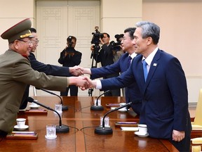 South Korean National Security Adviser Kim Kwan-jin (R), South Korean Unification Minister Hong Yong-pyo (2nd R), Secretary of the Central Committee of the Workers' Party of Korea Kim Yang Gon (2nd L), and the top military aide to the North's leader Kim Jong Un Hwang Pyong-so (L), shake hands during the inter-Korean high-level talks at the truce village of Panmunjom inside the Demilitarized Zone separating the two Koreas, South Korea, in this picture provided by the Unification Ministry and released by Yonhap on August 22, 2015. Top aides to the leaders of North and South Korea met at the Panmunjom truce village straddling their border on Saturday, raising hopes for an end to a standoff that put the rivals on the brink of armed conflict. REUTERS/the Unification Ministry/Yonhap