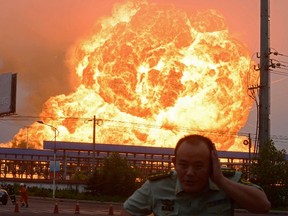 A policeman (R) and firemen (lower L) run from the scene after an explosion at a chemical plant in Rizhao, east China's Shandong province on July 16, 2015.   AFP PHOTO