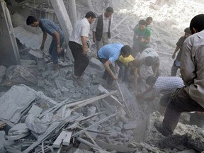 This photo released by the Douma Revolution News Network on their Facebook page, shows Syrians looking for bodies under debris of destroyed buildings following a Syrian government airstrike on the Damascus suburb of Douma, Syria, Saturday, Aug. 22, 2015. (Firas Abdullah/Douma Revolution News Network Facebook page via AP)