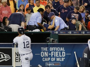 A fan is helped onto a stretcher after being hit with a foul ball off the bat of Tigers' Anthony Gose (foreground) during the eighth inning against the Rangers at Comerica Park in Detroit on Friday, Aug. 21, 2015. (Duane Burleson/AP Photo)