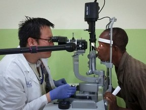 In this photo taken Friday, July 31, 2015, Dr. Zan Yeong, left, an eye specialist for a joint Liberian-American Ebola initiative known as the Partnership for Research on Ebola Vaccine in Liberia (PREVAIL), examines the eyes of Ebola survivor Abraham Moses, who has problems with his vision, at the John F. Kennedy Medical Center in Monrovia, Liberia.  (AP Photo/Wade Williams)