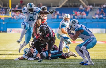 Ottawa RedBlacks' Jeremiah Johnson scores a touchdown against Toronto Argonauts Rickey Foley, right, and Euclid Cummings, left, during the first half of CFL football action in Toronto on Sunday, August 23, 2015. THE CANADIAN PRESS/Mark Blinch