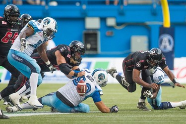 Ottawa RedBlacks' quarterback Henry Burris, right, fumbles the ball as his teammate Jon Gott, second left, dives for the ball against Toronto Argonauts Vincent Desloges, left, and Daryl Waud, centre, during the second half of CFL football action in Toronto on Sunday, August 23, 2015. THE CANADIAN PRESS/Mark Blinch