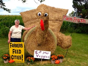 Laurie Neubrand stands proudly next to her straw sculpture of a giant turkey on her farm on Line 49 north of Bornholm. Neubrand used a red neck pillow form the dollar store as the turkey's wattle. GALEN SIMMONS/MITCHELL ADVOCATE
