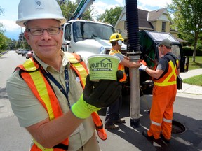 Barry Orr, a sewer control and outreach inspector for the City of London, shows one of the paper cups that they hope homeowners will use to dispose of household fats. (MORRIS LAMONT, The London Free Press)