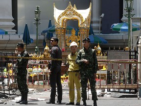 Police, soldiers, and other officials work near the statue of Phra Phrom, the Thai interpretation of the Hindu god Brahma, at the Erawan Shrine at Rajprasong intersection the day after an explosion in Bangkok, Thailand, Tuesday, Aug. 18, 2015.  (AP Photo/Sakchai Lalit)