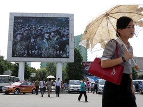 In this Friday, Aug. 21, 2015 photo, a woman walks past a propaganda movie shown on a large screen in Pyongyang, North Korea. North Koreans are accustomed to being told they are on the brink of war with their southern neighbours and U.S. troops, and as talks with South Korea in the truce village of Panmunjom dragged on this weekend one had to look hard in the North Korean capital of Pyongyang to find signs of a brewing crisis. (AP Photo/Dita Alangkara)