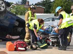 Ottawa Paramedics treat a driver who suffered minor injuries after her vehicle slammed into another car and flipped on Merivale Rd. Tuesday morning. The vehicle her car struck then careened into a dump truck. SAM COOLEY / OTTAWA SUN