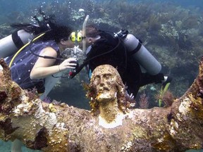 Kimberly Triolet(L) and Jorge Rodriguez kiss after being married next to the Christ of the Deep statue August 25, 2015, in the Florida Keys National Marine Sanctuary off Key Largo, Florida. The wedding helped to mark the 50th anniversary of the August 25, 1965, installation of the 9-foot-tall bronze sculpture that is a symbol for Key Largo's John Pennekamp Coral Reef State Park, America's first underwater preserve that is part of the sanctuary. It is a replica of the "Christ of the Abyss" that was placed in Italian waters in 1954. AFP PHOTO / HANDOUT / FLORIDA KEYS NEWS BUREAU / BOB CARE