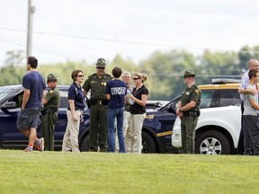West Virginia Police and school officials help parents reunite with their children at Philip Barbour High School following a "hostage-type situation" Tuesday, Aug. 25, 2015, in Philippi, W.Va. A report of someone with a gun inside the school led authorities to isolate and arrest a suspect in the building Tuesday, State Police said. (AP Photo/Ben Queen)