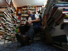 In this Aug. 19, 2015 photo, Jose Alberto Gutierrez sits among piles of books at his home in Bogota, Colombia. A second-grade education has not stopped garbage collector Jose Gutierrez from bringing the gift of reading to thousands of Colombian children. (AP Photo/Fernando Vergara)