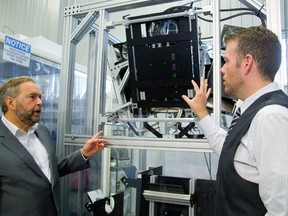 NDP leader Tom Mulcair talks to Sciencetech president Scott Hafekost about their solar furnace they have built for a US university that hopes to study changes in materials at extreme temperatures. Hafekost said they use four lamps focused on a 1 inch spot and are able to reach temperatures in excess of 2700 degrees, hot enough to melt zirconium in London, Ont. on Wednesday August 26, 2015. (MIKE HENSEN, The London Free Press)