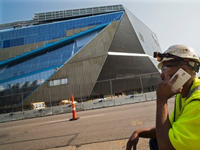 Apprentice electrician Coshay Murray talks on a phone in front of the Minnesota Vikings' new stadium in Minneapolis, Wednesday, Aug. 26, 2015. A construction worker at the new stadium died and a second worker was seriously injured when they fell Wednesday morning while doing roofing work. Murray  said,"we are all a little traumatized today." (Richard Tsong-Taatarii/Star Tribune via AP)