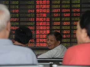 Investors chat in front of an electronic board showing stock information at a brokerage house in Shanghai, August 26, 2015. (REUTERS/China Daily)