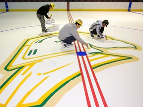 Budweiser Gardens crew Shawn Patton, Shelly Schelhaas and Randy Laskey paint the Knights logo at centre ice.  (MIKE HENSEN, The London Free Press)