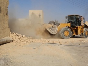 This picture released late Thursday, Aug. 20, 2015, by an Islamic State militant-affiliated website, shows a bulldozer of the Islamic State militants destroying the Saint Eliane Monastery near the town of Qaryatain which IS captured in early August, in Homs province, Syria. A priest and activists say the Islamic State group has demolished an ancient monastery in central Syria. A Christian clergyman told The Associated Press in Damascus that IS militants also wrecked a church inside the monastery that dates back to the first Christian centuries. The priest, who spoke Friday on condition of anonymity for fear of reprisals, said the monastery included an Assyrian Catholic church. (Islamic State militant website via AP)