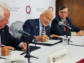 Florida Tech President and CEO Anthony J. Catanese, left, and Dwayne McCay, Florida Tech executive vice president, right watch as Apollo 11 astronaut Buzz Aldrin signs paper work formalizing the establishment of the Buzz Aldrin Space Institute at the university, Thursday, Aug. 27, 2015 in Melbourne, Fla.(Craig Rubadoux/Florida Today via AP)