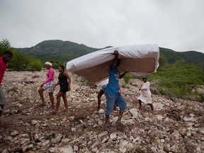 Residents work to salvage personal items from the site of a mudslide in rain-soaked Montrouis, Haiti, Saturday, Aug. 29, 2015. Erika dissipated early Saturday, but it left devastation in its path on the small eastern Caribbean island of Dominica, authorities said. In Haiti, one person died in the mudslide just north of Port-au-Prince. (AP Photo/Dieu Nalio Chery)