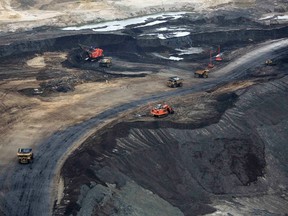 Heavy earth moving machinery move raw tars sands at the Syncrude tar sands mining operations near Fort McMurray, Alberta, in this September 17, 2014 file photo. Canada's oil sands mining companies are perilously close to or already operating at loss after six months of plunging crude prices, company documents and checks with producers show, but many say they still have no plans to cut existing output at their vast bitumen strip-mines in northern Alberta.  (REUTERS/Todd Korol/Files)