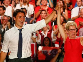Federal Liberal leader Justin Trudeau (L) has his hand held aloft  by  Ontario Premier Kathleen Wynne (R) at a Liberal rally held at the Daniels Spectrum in Regent Park on Monday August 17, 2015. Jack Boland/Toronto Sun/Postmedia Network