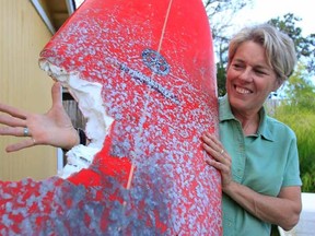 At home in Los Osos, Calif., Elinor Dempsey, 54, shows her surfboard which a shark bit earlier Saturday, Aug. 29, 2015 while she was in Morro Bay. She was uninjured in the attack. (Laura Dickinson/The Tribune (of San Luis Obispo) via AP)