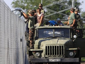 Hungarian soldier adjusts the razor wire on a fence near the town of Asotthalom, Hungary, August 30, 2015. About 100,000 migrants, many of them from Syria and other conflict zones in the Middle East, have taken the Balkan route into Europe this year, heading via Serbia for Hungary and Europe's Schengen zone of passport-free travel. (REUTERS/Bernadett Szabo)